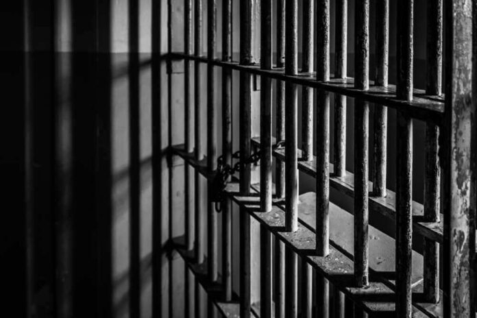 Black and white prison cell bars in dim light.