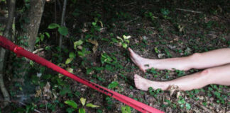 Bare feet visible near caution tape in a wooded area