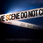 Police tape reading 'CRIME SCENE DO NOT CROSS' in a dark setting