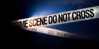 Police tape reading 'CRIME SCENE DO NOT CROSS' in a dark setting