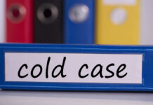 Buried Under Garage — Name Finally Revealed Blue binder labeled 'cold case' with other colored binders in the background