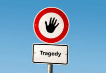 Road sign with hand stop symbol and a lower sign reading Tragedy