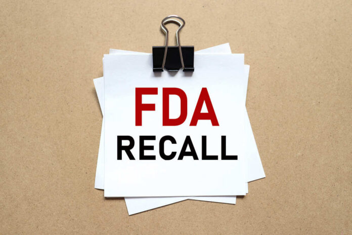 Fda,Recall.,The,Paper,Is,Clamped,With,A,Clerical,Clip. A notice labeled 'FDA RECALL' clipped to white papers on a brown background