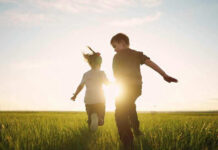 Children running in a field at sunset.