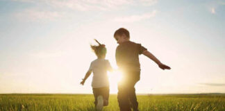 Children running in a field at sunset.