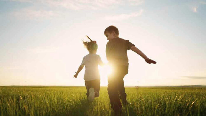 Children running in a field at sunset.