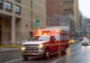 Ambulance with flashing lights driving on a wet city street