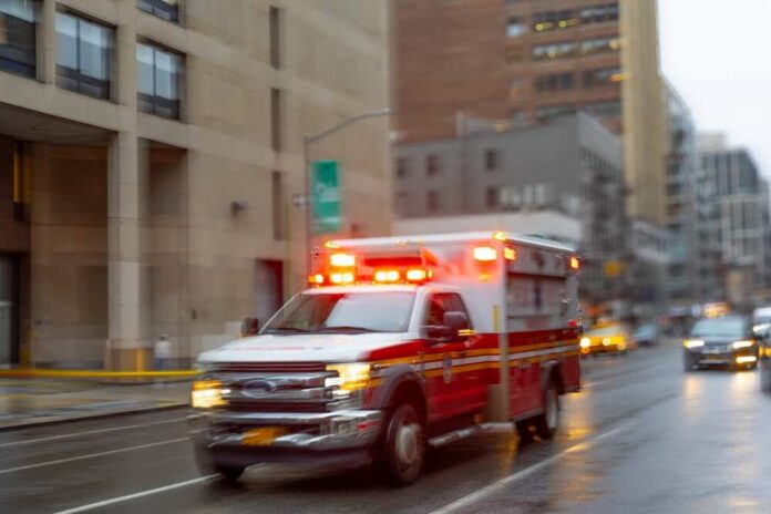 Ambulance with flashing lights driving on a wet city street