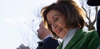 Nancy Pelosi smiling while holding papers outdoors
