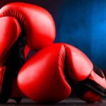 Red boxing gloves on a dark, textured surface.