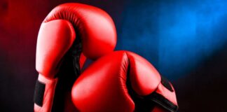 Red boxing gloves on a dark, textured surface.