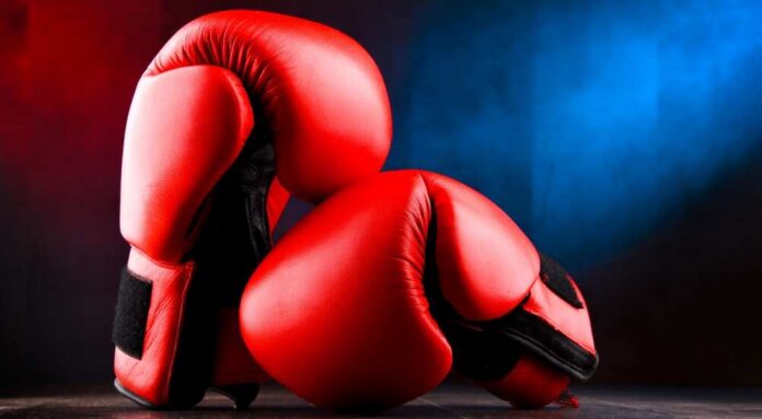 Pair,Of,Red,Leather,Boxing,Gloves. Red boxing gloves on a dark, textured surface.