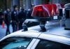 Woman Killed As Trunk Full Of Fireworks Erupts Police car roof with lights, officers in background.