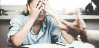 Stressed woman with hands on face at a desk.