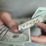 Hands holding stack of one hundred dollar bills