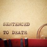 Typewriter typing the phrase 'Sentenced to Death' on aged paper