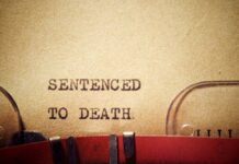 Typewriter typing the phrase 'Sentenced to Death' on aged paper