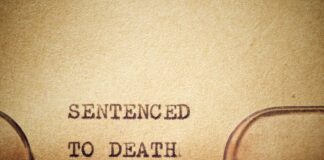 Typewriter typing the phrase 'Sentenced to Death' on aged paper
