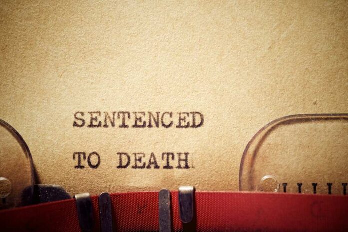 Typewriter typing the phrase 'Sentenced to Death' on aged paper