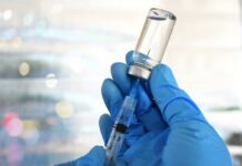 A gloved hand holding a syringe and a vial of liquid
