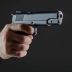 Hand holding a semi-automatic pistol pointed forward