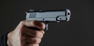 Hand holding a semi-automatic pistol pointed forward