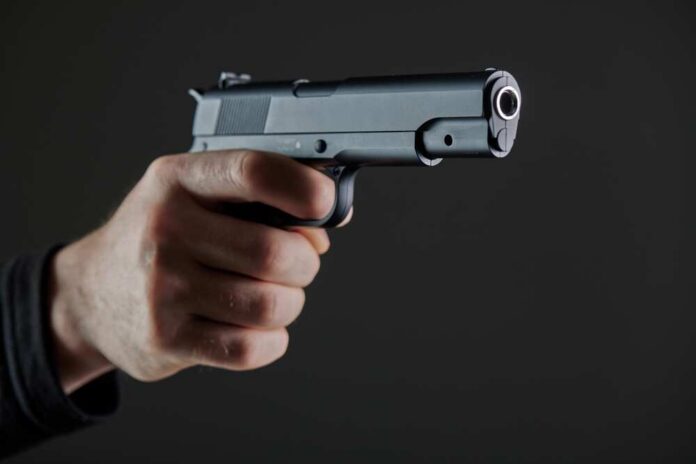 Hand holding a semi-automatic pistol pointed forward