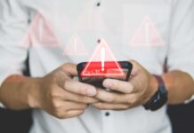 Hands holding a smartphone with warning icons overlay