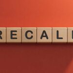 Wooden letter tiles spelling recall on an orange background