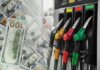 Fuel pump nozzles next to spread of U.S. hundred-dollar bills