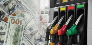 Fuel pump nozzles next to spread of U.S. hundred-dollar bills