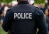 Back view of a police officer wearing a uniform with 'POLICE' displayed