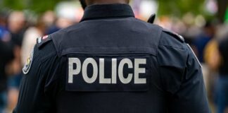 Back view of a police officer wearing a uniform with 'POLICE' displayed