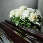 Young Star’s Battle Ends – Fans Mourn Her Death A floral arrangement of white roses and greenery on a polished casket