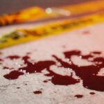 Blood droplets on pavement near yellow caution tape