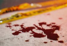 Blood droplets on pavement near yellow caution tape