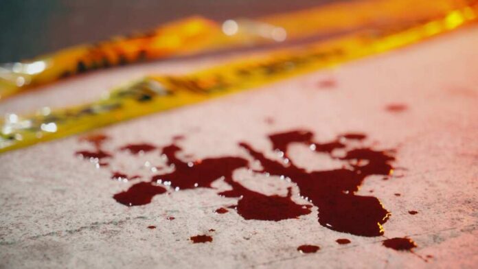 Blood droplets on pavement near yellow caution tape