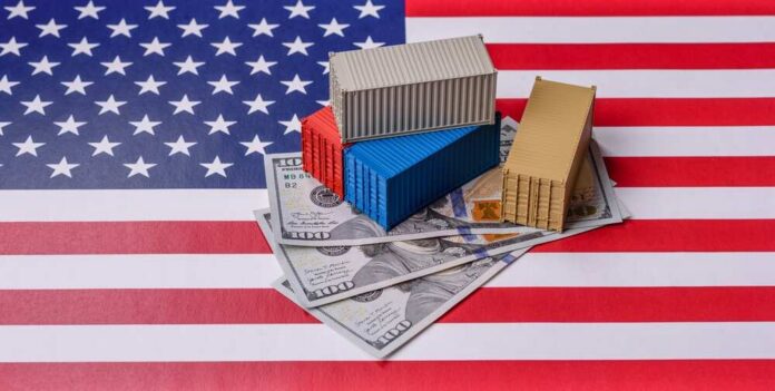 Cargo,Containers,On,The,Us,Flag,As,A,Conceptual,Backdrop Mini shipping containers on US dollars over an American flag