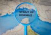 Magnifying glass highlighting the Strait of Hormuz on a map
