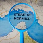 Magnifying glass highlighting the Strait of Hormuz on a map