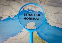 Magnifying glass highlighting the Strait of Hormuz on a map