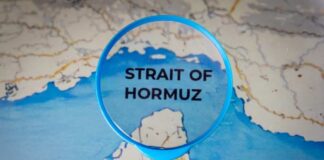 Magnifying glass highlighting the Strait of Hormuz on a map
