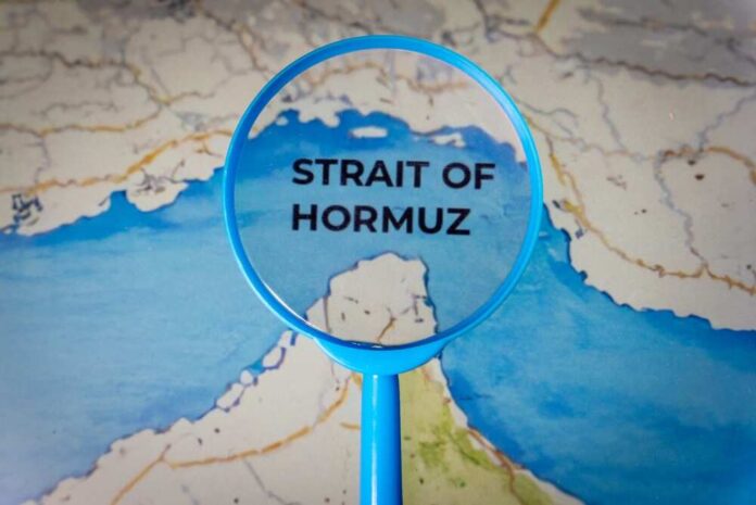 Magnifying glass highlighting the Strait of Hormuz on a map