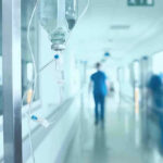 Lightning Blasts Prison Walk — 16 Down Hospital corridor with IV drip and healthcare worker.