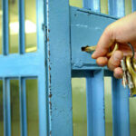 Hand unlocking blue metal door with keys.