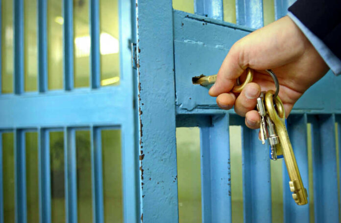 Hand unlocking blue metal door with keys.