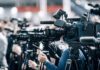 Broadcast cameras on tripods at a press event