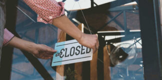 Person flipping closed sign on glass door