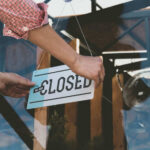 Coffee Giant Hit Hard – Massive Store Closings Person flipping closed sign on glass door