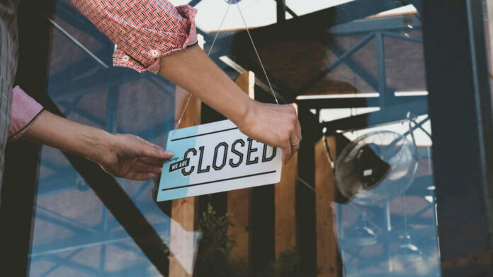 Person flipping closed sign on glass door